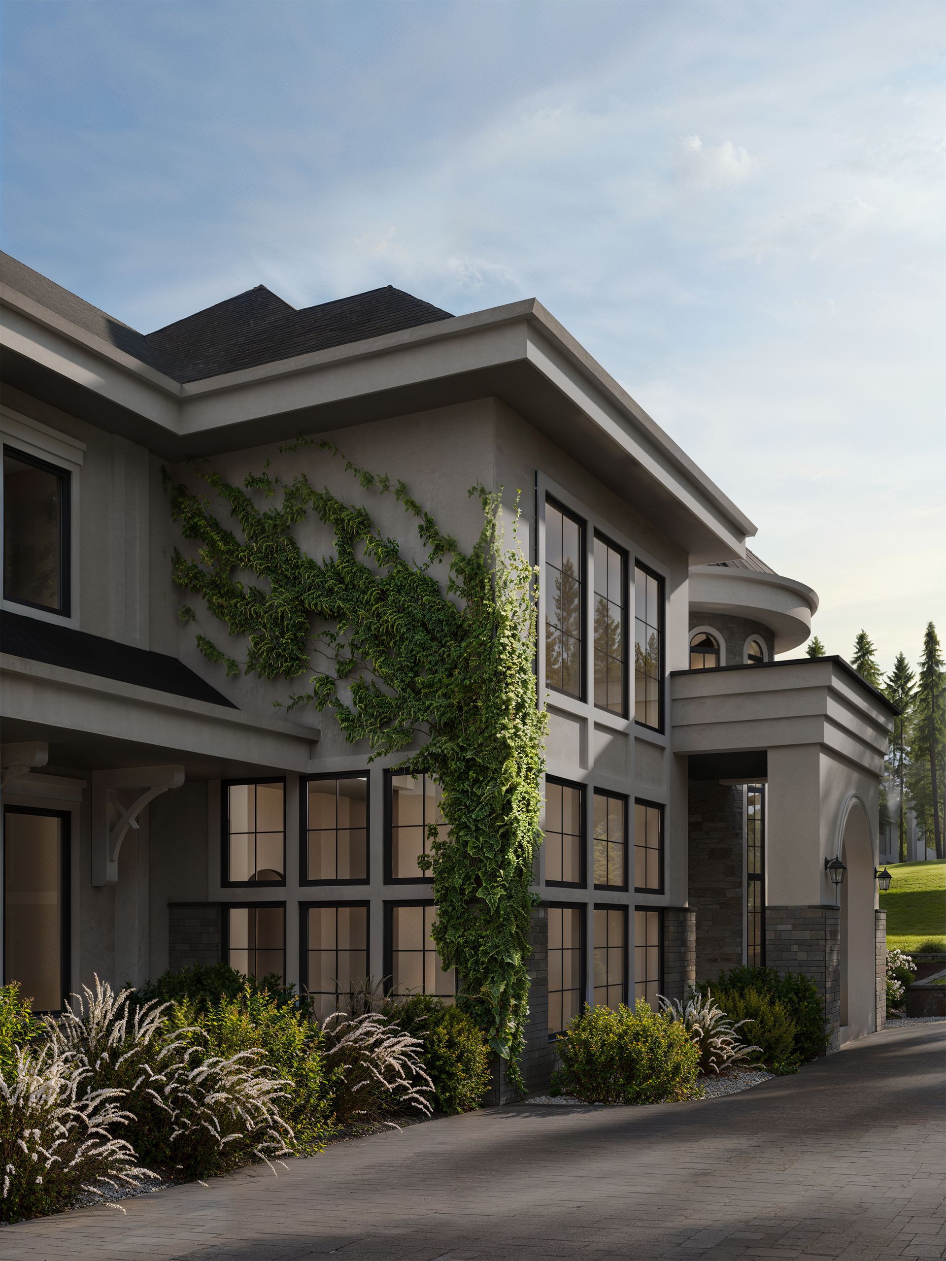 A modern, light-gray multi-story house with black window frames, crawling ivy, and landscaping along a gravel driveway.