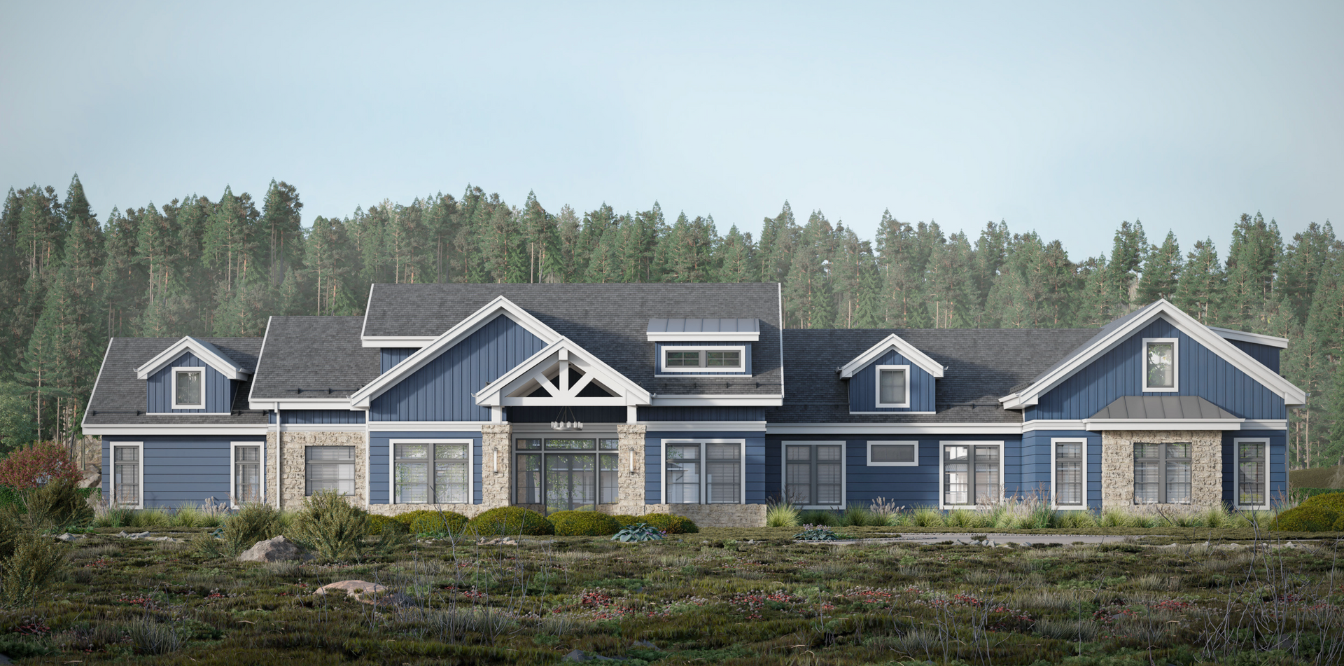 A large, blue-sided, multi-gabled house with stone accents, set against a backdrop of a dense forest.
