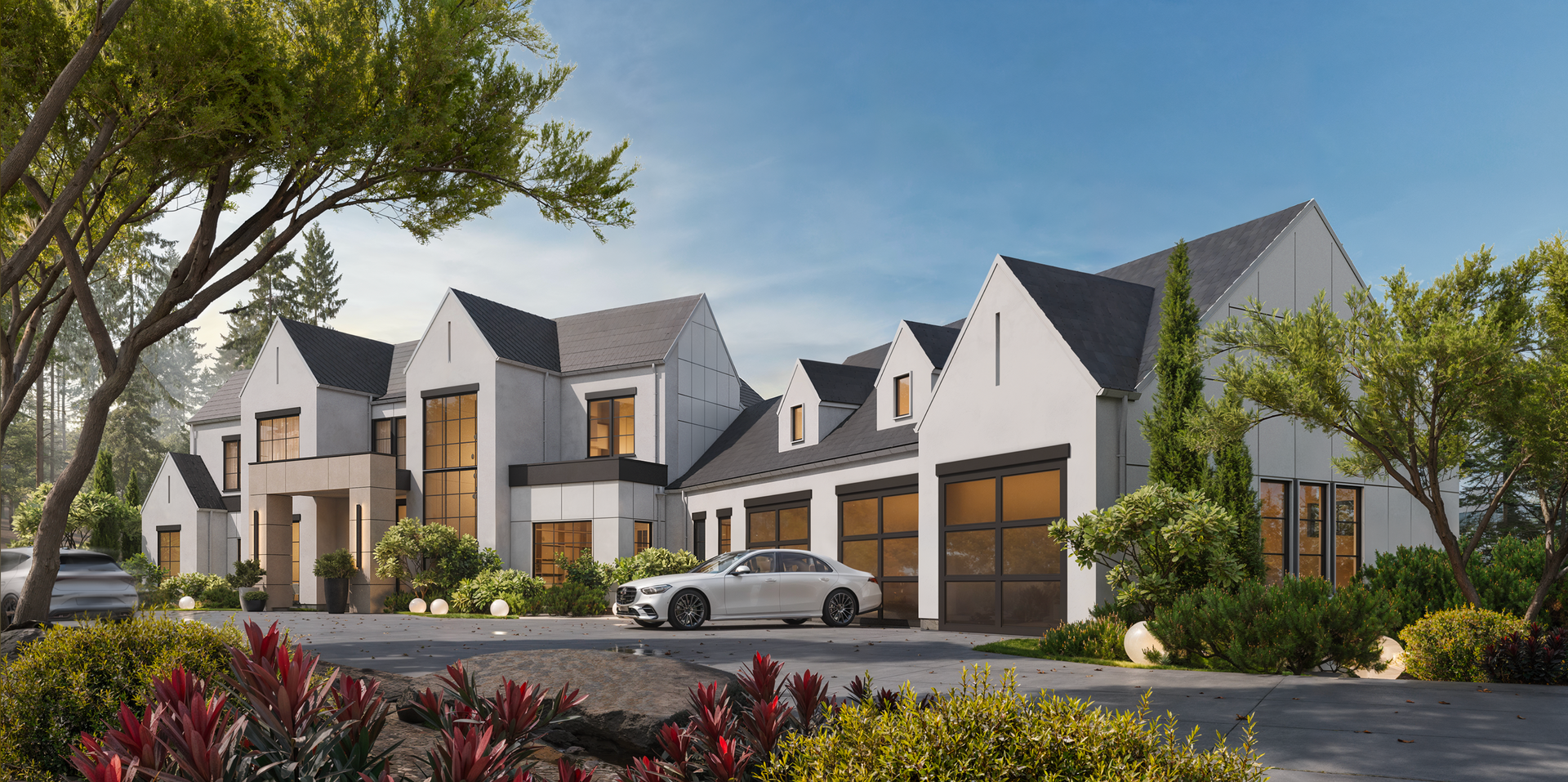 A modern white multi-gabled luxury house with dark roofs and a paved driveway, surrounded by greenery and trees.