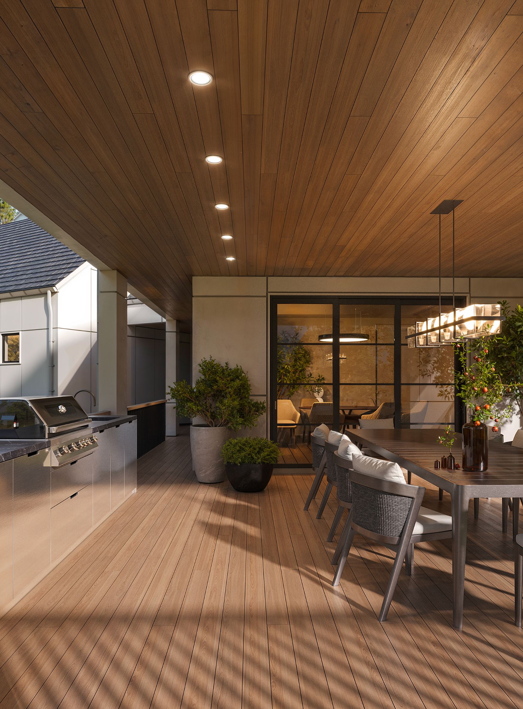 A covered outdoor patio featuring wood-paneled walls, a stainless steel grill, a dining table with chairs, and recessed lighting.