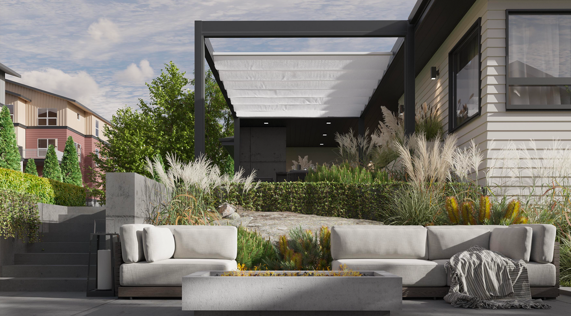 A modern outdoor patio with a fire pit, cushioned sofa, and a pergola attached to the side of a light-colored house.