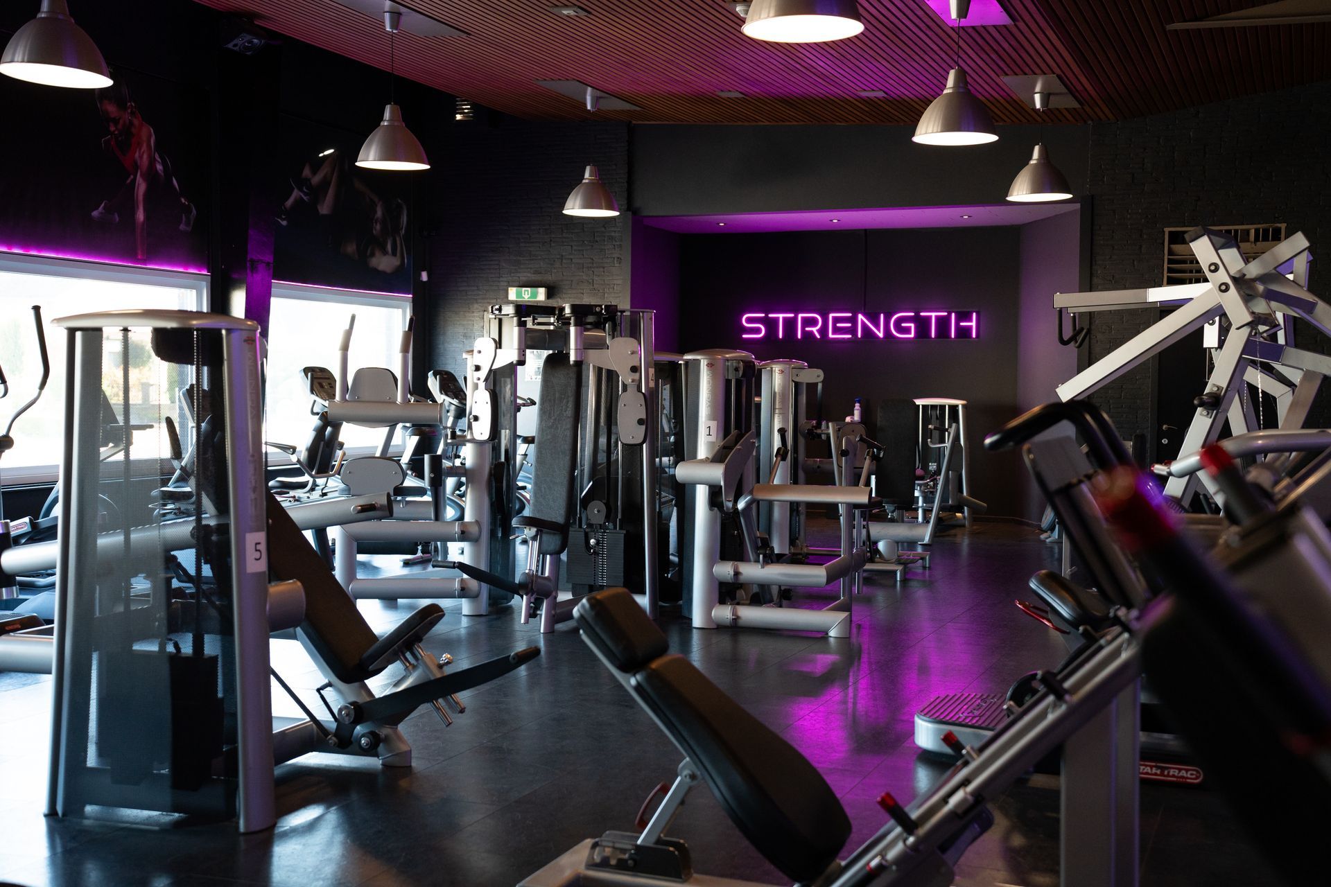 Modern fitnesscentrum met fitnessapparaten, paarse verlichting en een neonbord met de tekst 