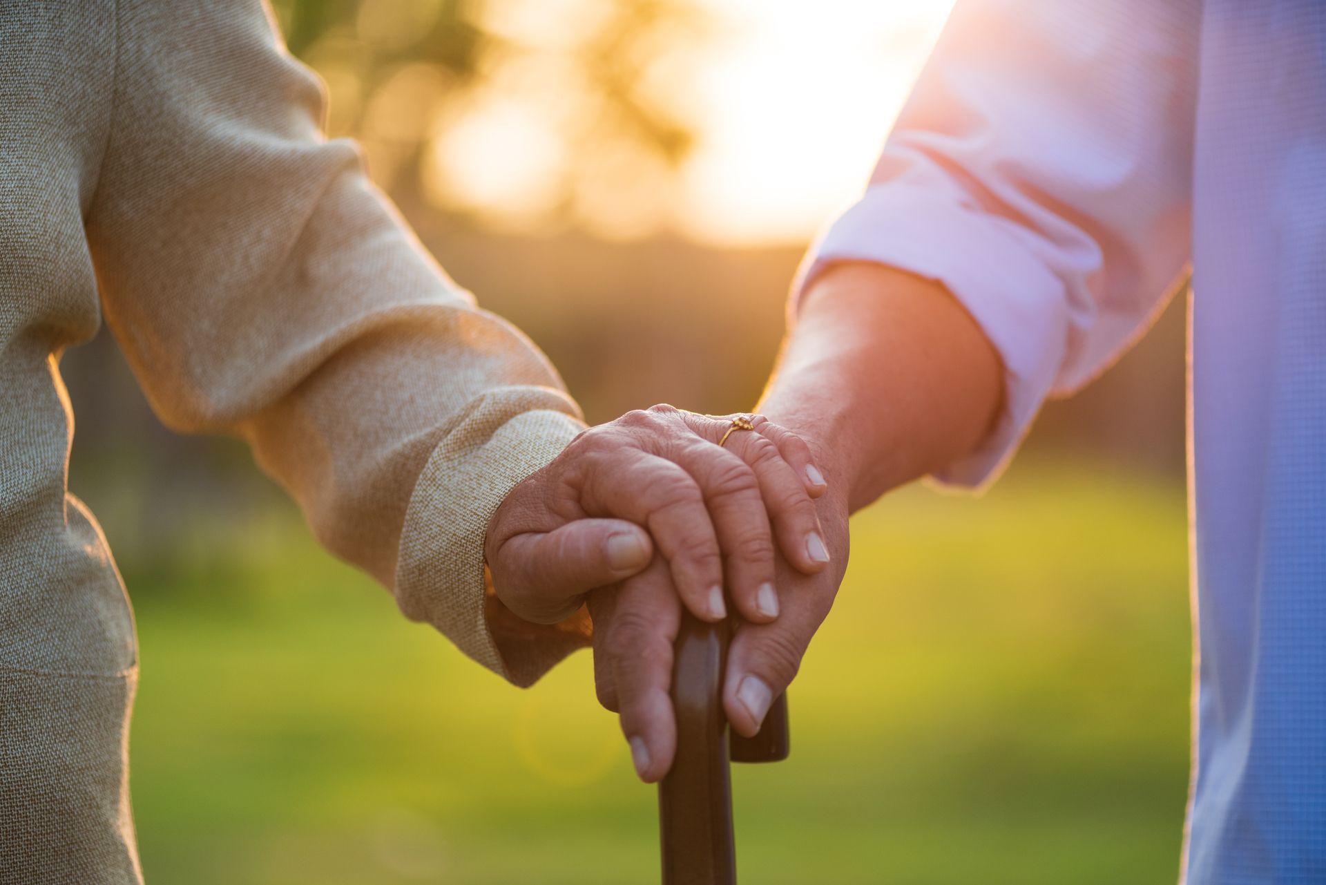 A woman is holding the hand of an older woman holding a cane.