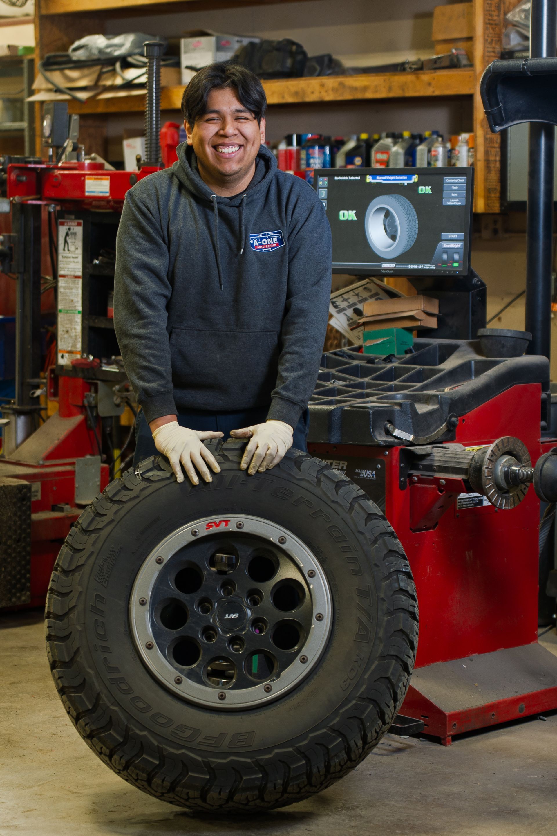 Car's front brake assembly lifted on a service lift, showing rotor, caliper, and suspension components.