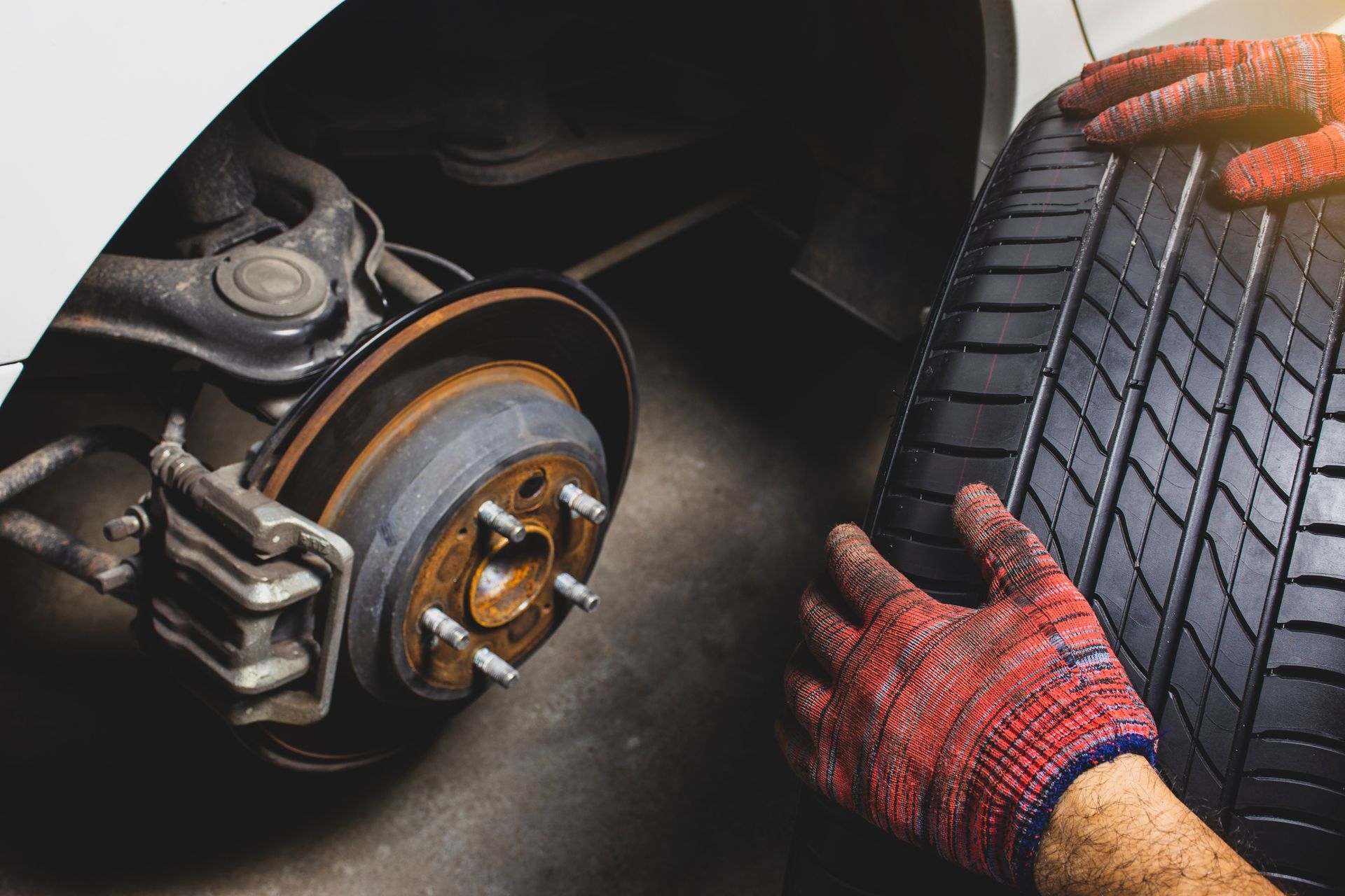 Mechanic in gloves performing a new tire installation on a white car at an auto repair shop. Mechanic in gloves performing a new tire installation on a white car at an auto repair shop.