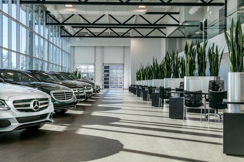 A row of mercedes cars are parked in a showroom.