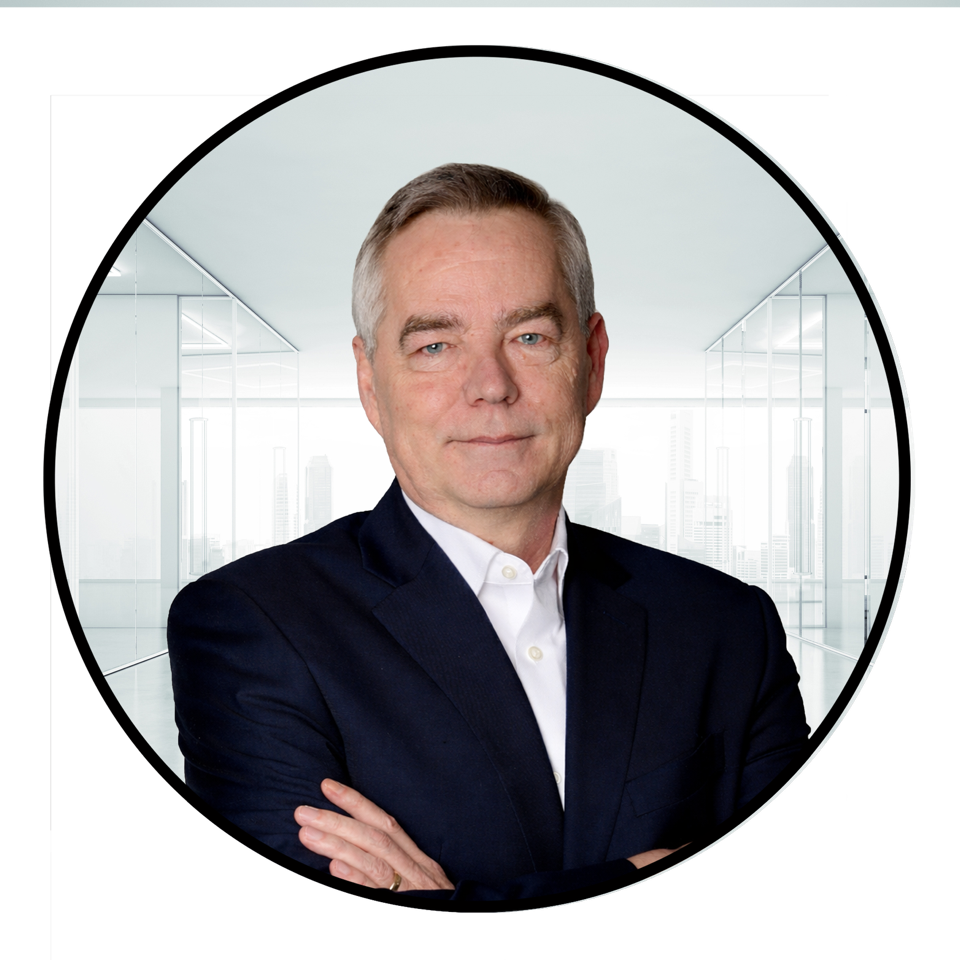 Man in a dark suit with arms crossed, in a bright office setting.