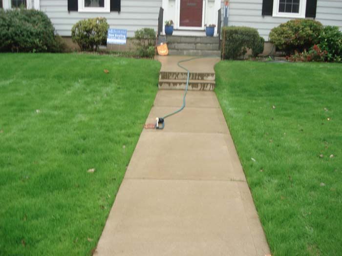 A hose is attached to a sidewalk in front of a house.