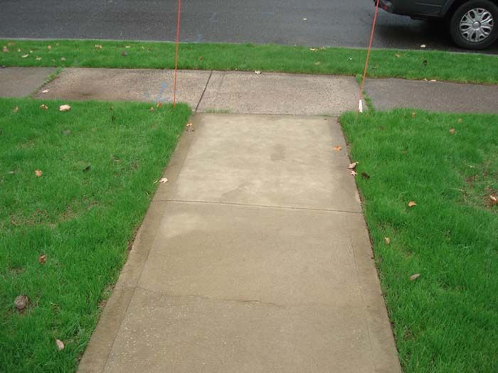 A sidewalk with a car parked on the side of it.