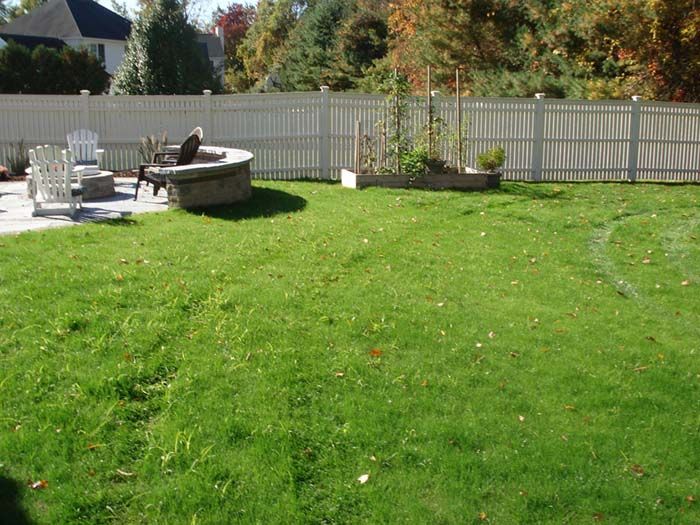 A backyard with a white fence and a fire pit