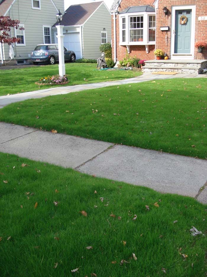 A brick house with a lush green lawn in front of it