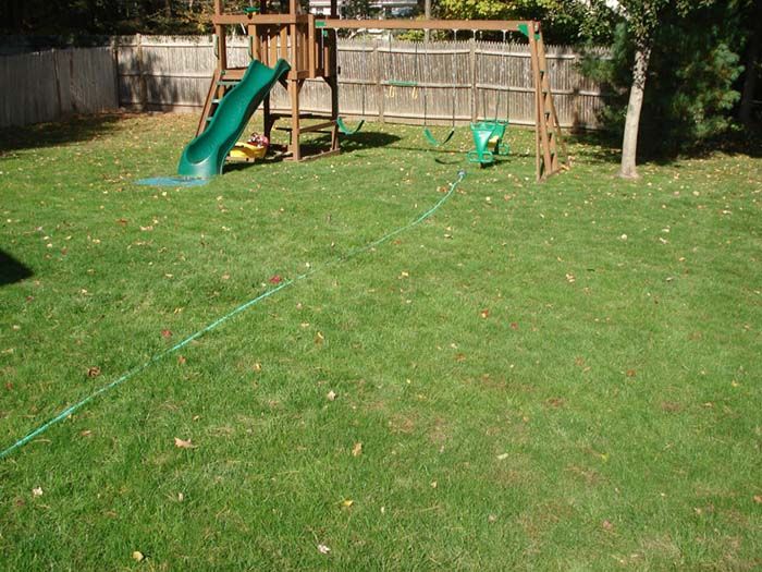 A playground with a slide and swings in a backyard