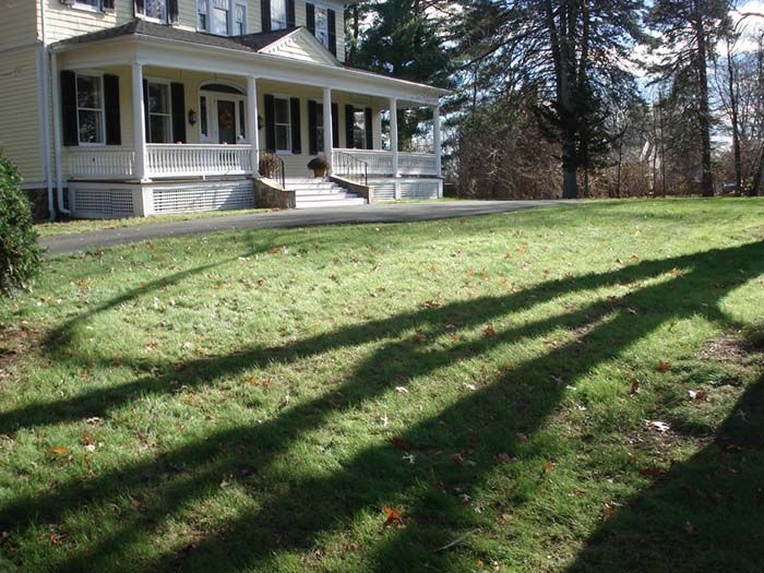 A house with a large porch and a lush green lawn