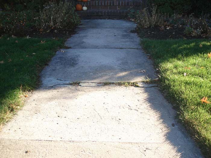 A concrete walkway leading to a fence with pumpkins on it