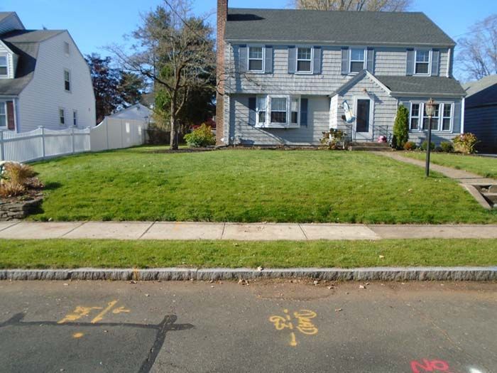 A house with a lush green lawn is surrounded by other houses