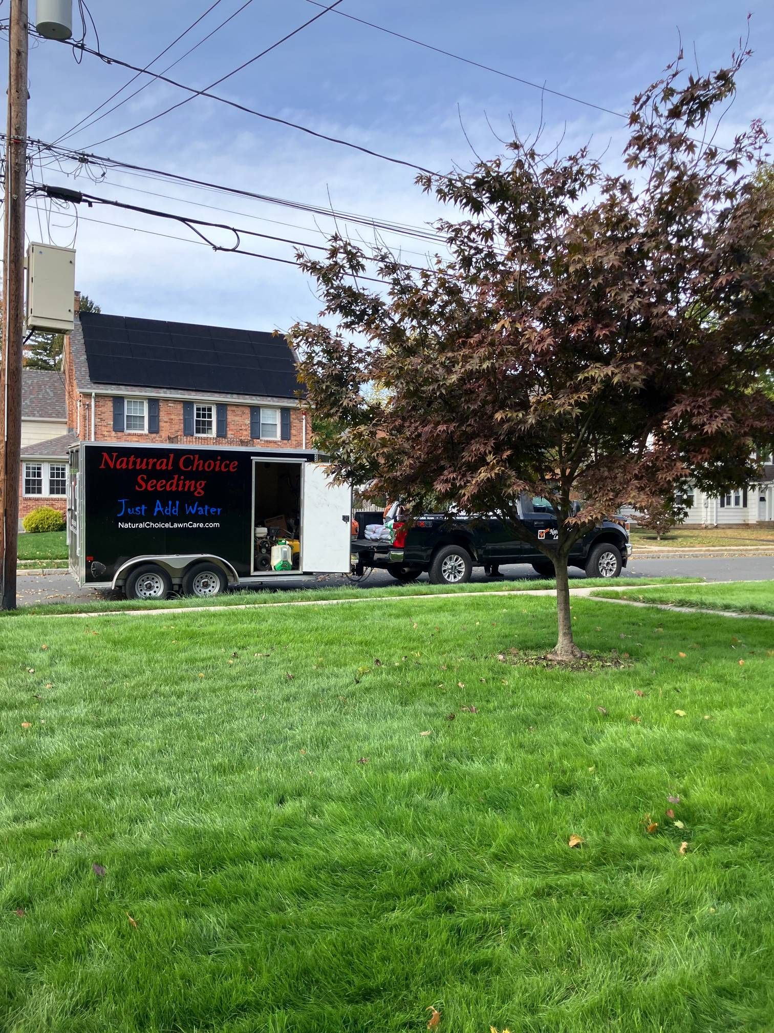 A trailer is parked in the grass in front of a house.