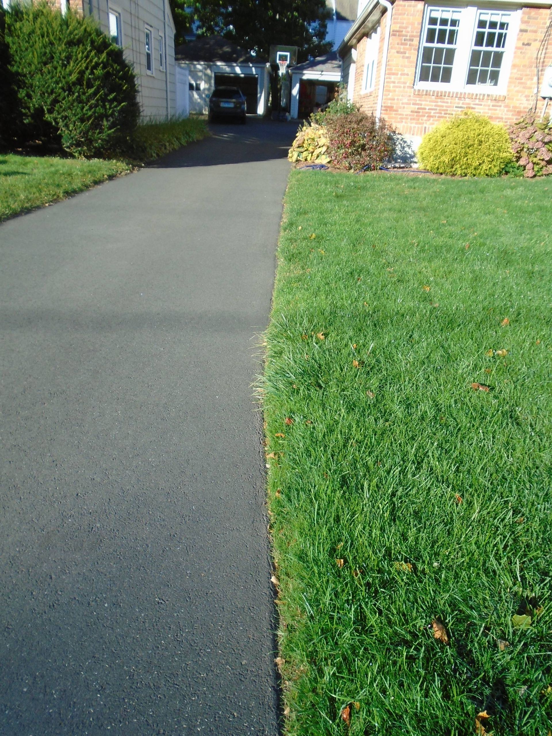 A driveway with a brick house in the background