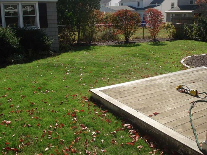 A lawn with a deck and a house in the background
