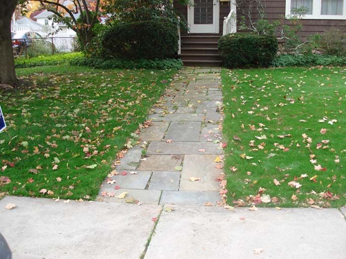 A stone walkway leading to a brown house