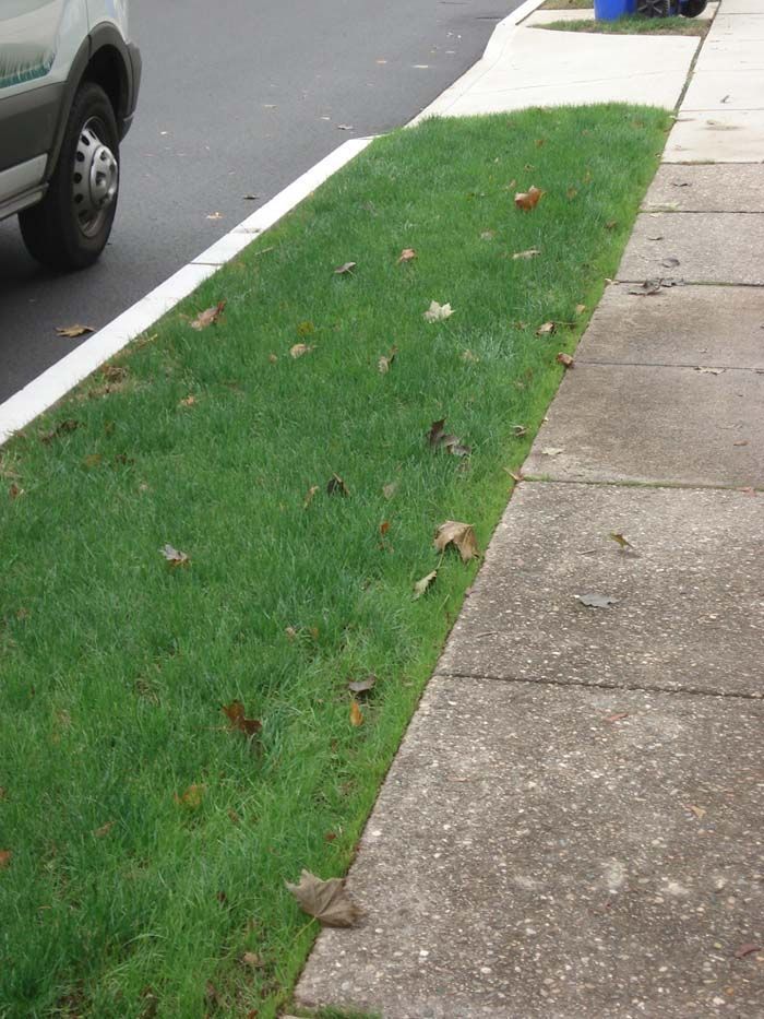 A car is parked on the side of the road next to a sidewalk.