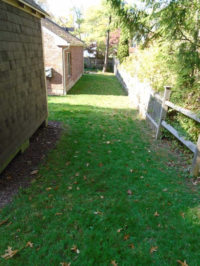A yard with a wooden fence and a brick building in the background