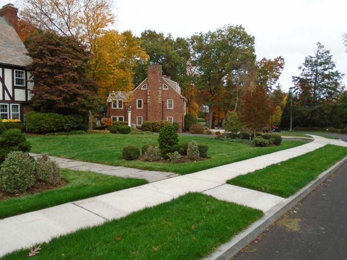 A brick house sits in the middle of a lush green neighborhood