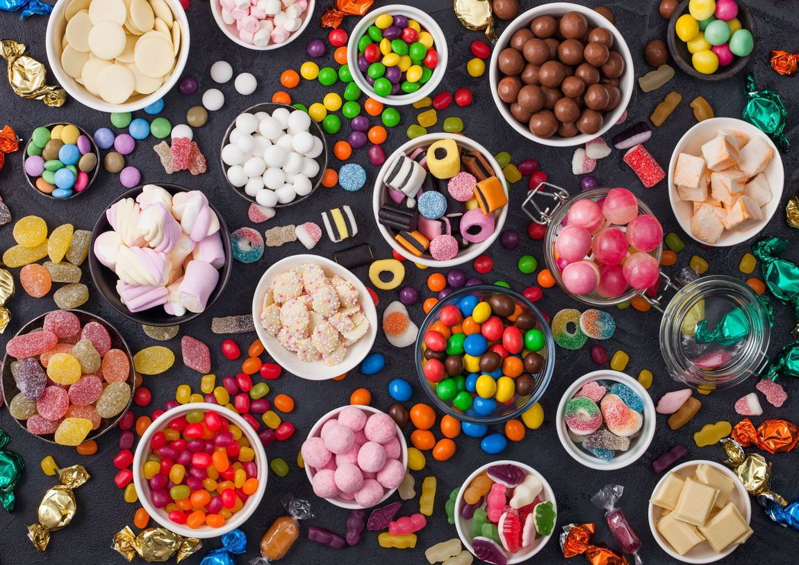 There are many different types of candy in bowls on the table.