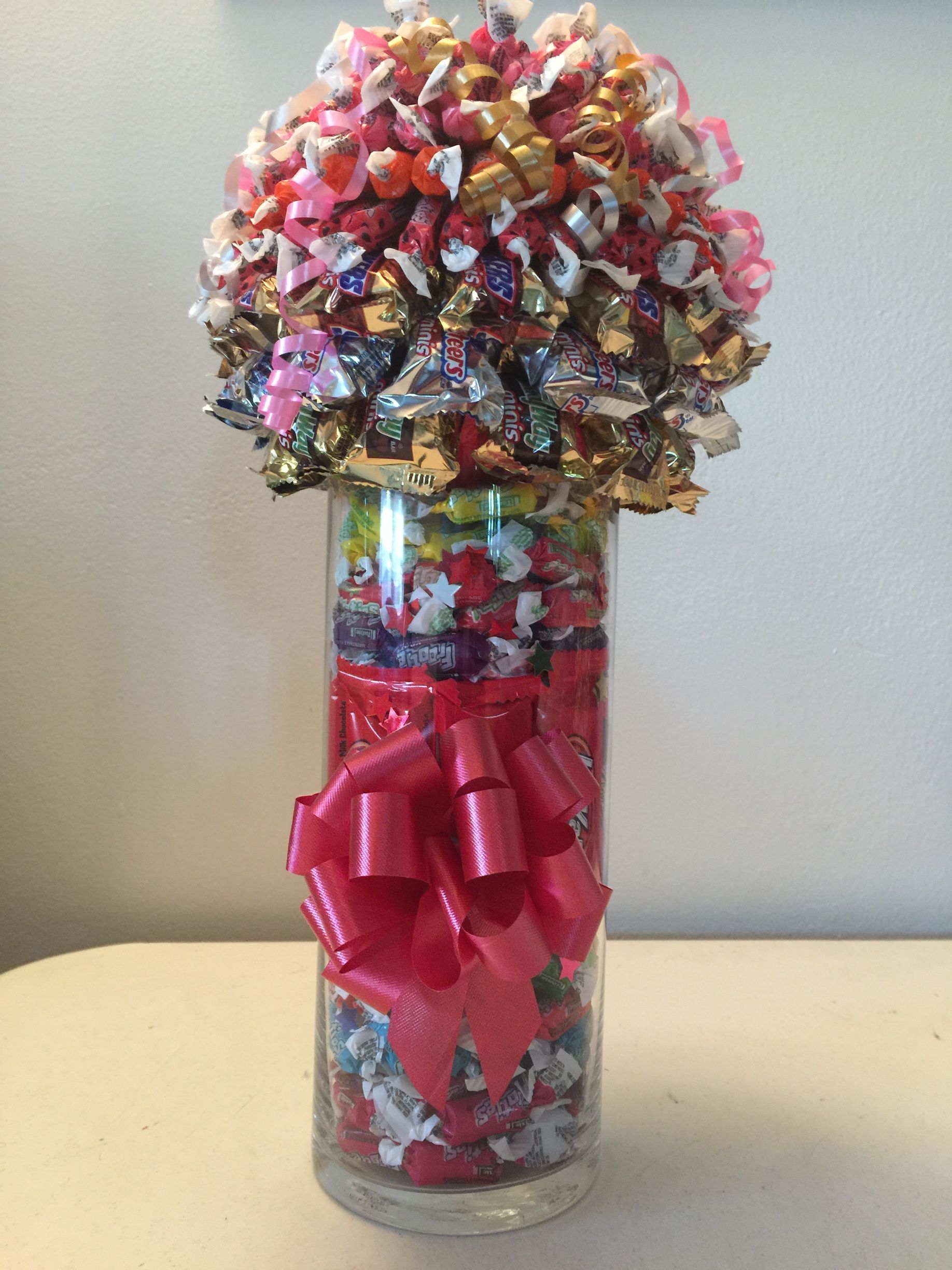 A bouquet of marshmallows is sitting on a wooden table next to three plastic containers of marshmallows.