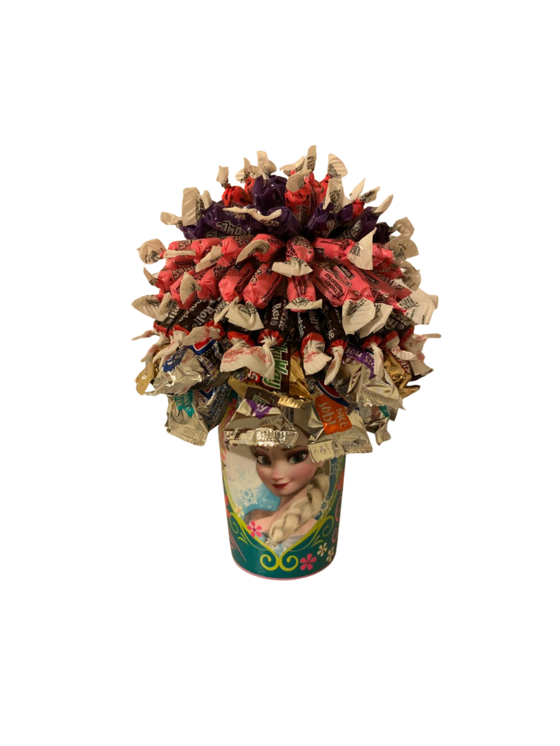 A bouquet of candy and marshmallows wrapped in pink paper on a table.