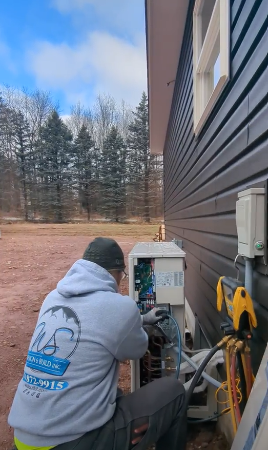 A man is working on an air conditioner outside of a house.