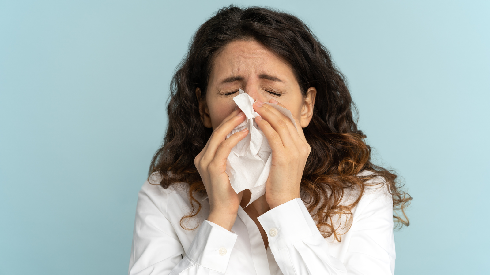 A woman is blowing her nose into a napkin.