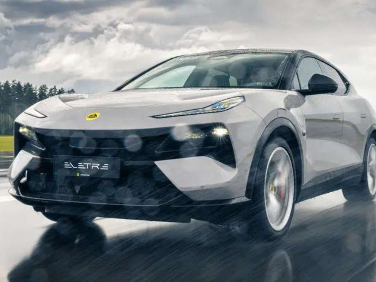 A white electric car is driving on a wet road in the rain.