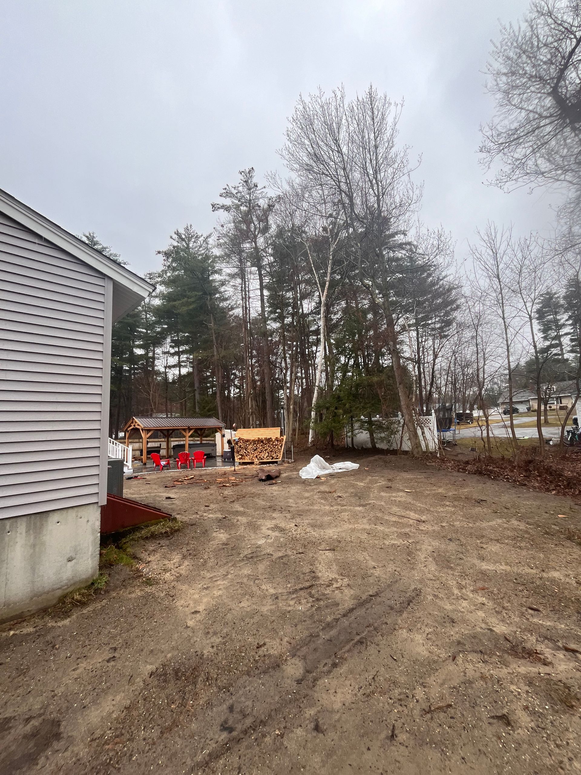 A dirt field with a house in the background and trees in the background.