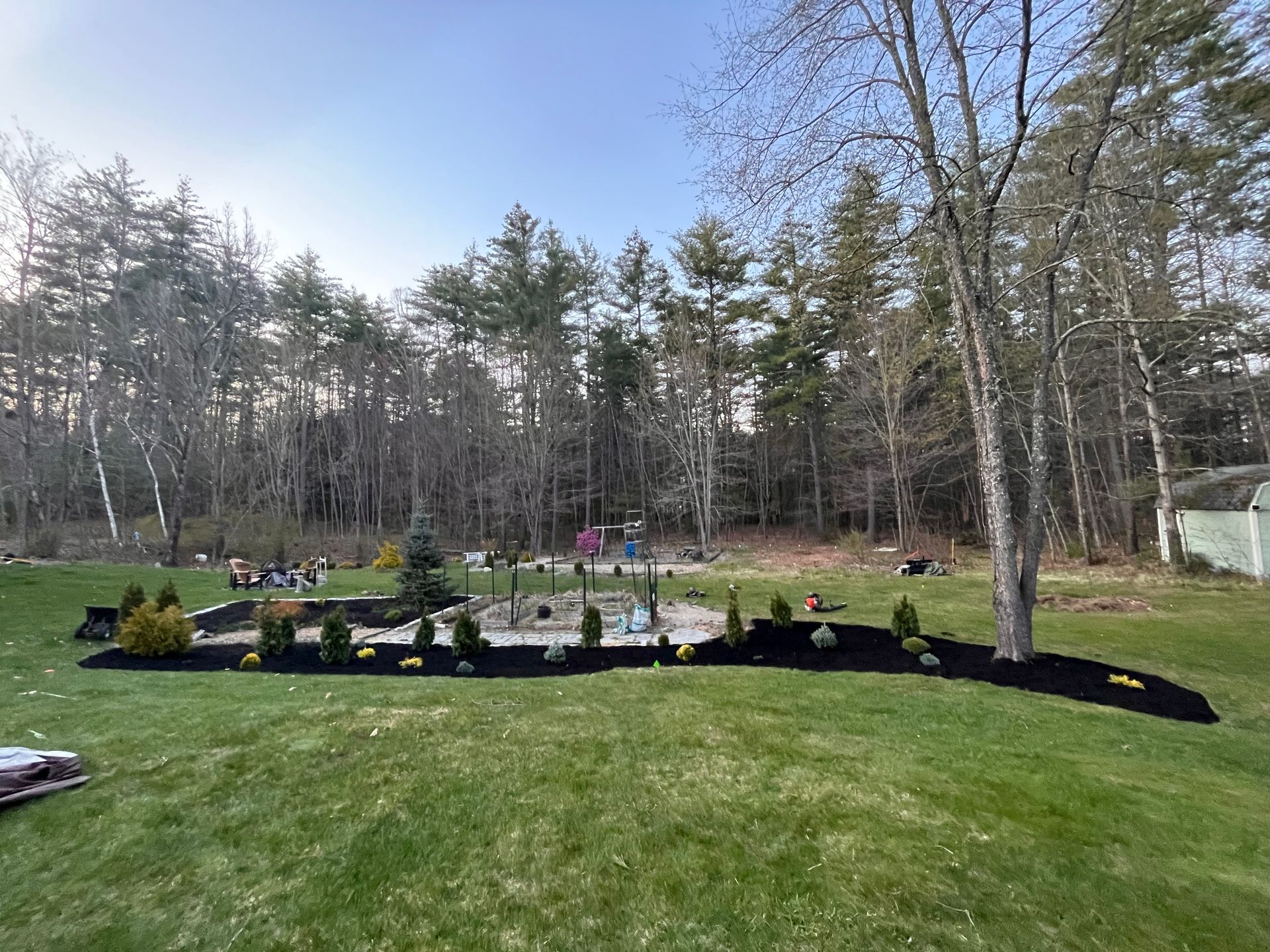 A backyard with a lush green lawn and trees in the background.