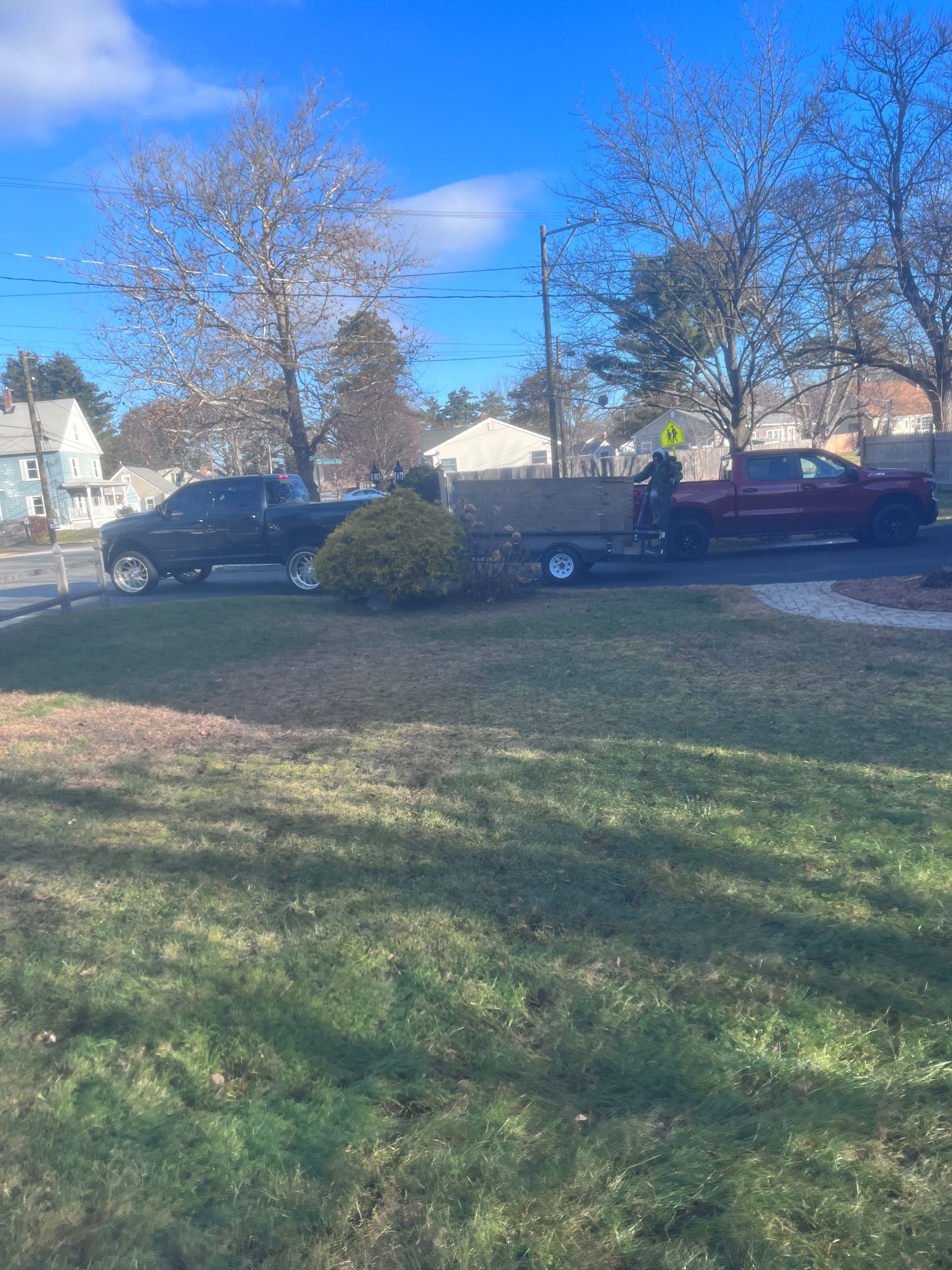 A red truck is towing a black truck on a trailer.