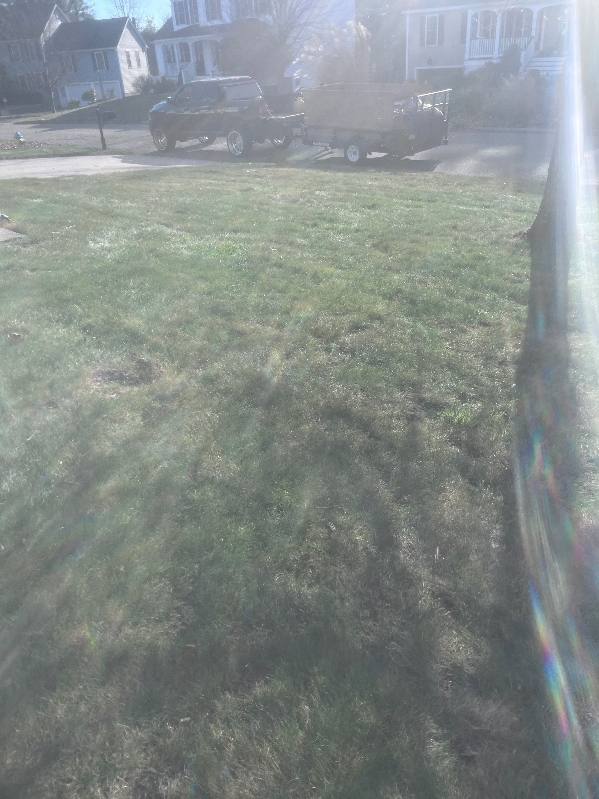 A car is parked in the grass in front of a house.