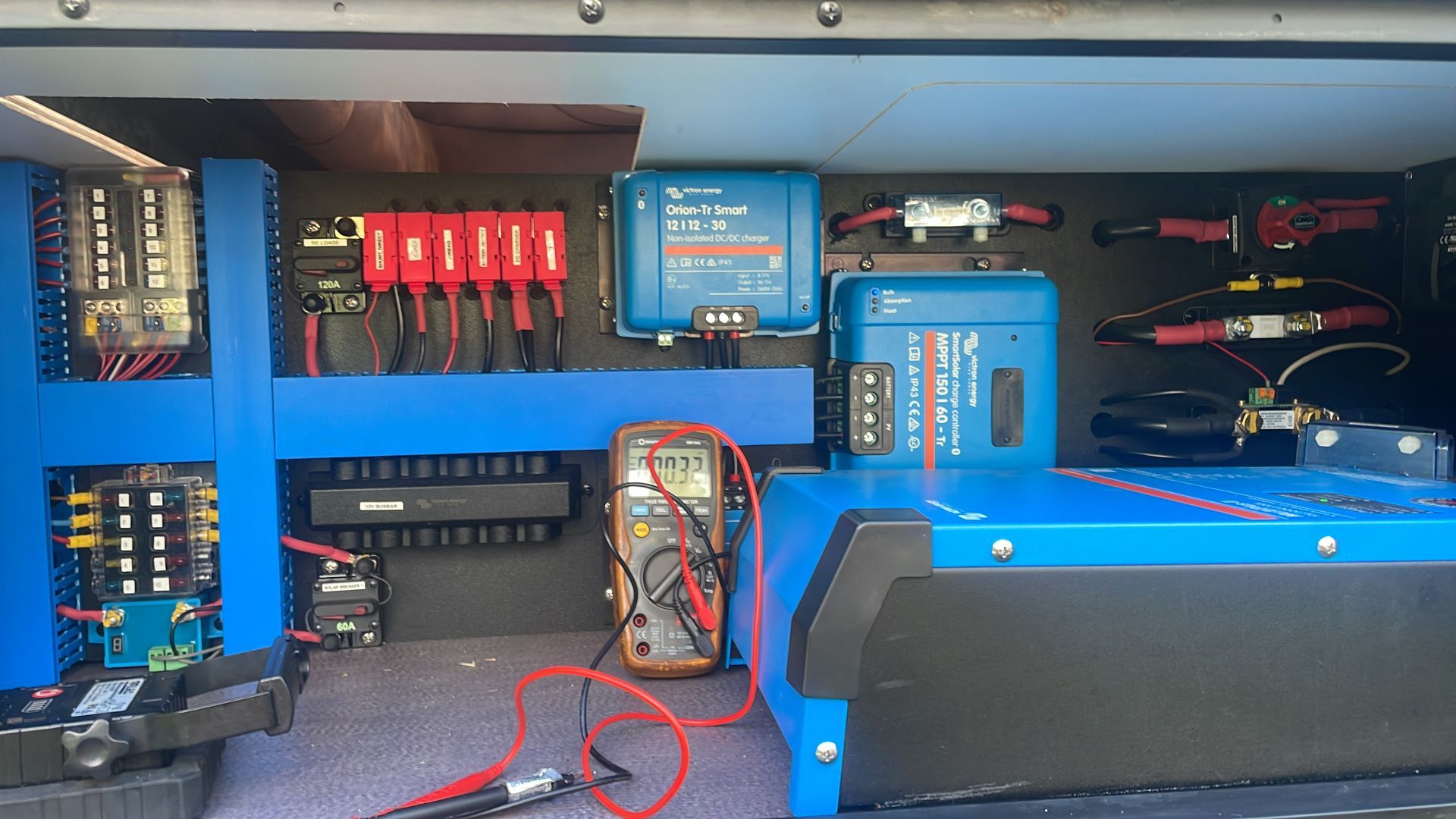 A Person Using a Multimeter to Test a Blue Electrical Panel — Glenn Rowe Auto Electrics In Palm Beach, QLD