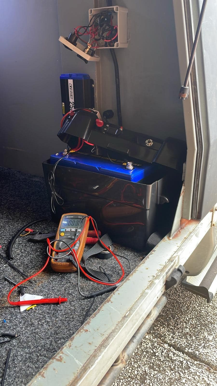 Multimeter Testing a Large Black Battery in a Vehicle — Glenn Rowe Auto Electrics In Palm Beach, QLD