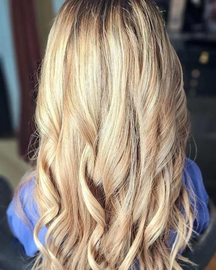 A woman with long blonde hair is wearing a blue shirt.