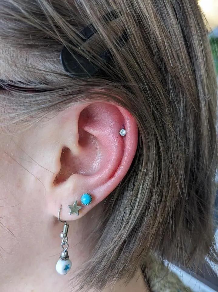A close up of a woman 's ear with multiple piercings.
