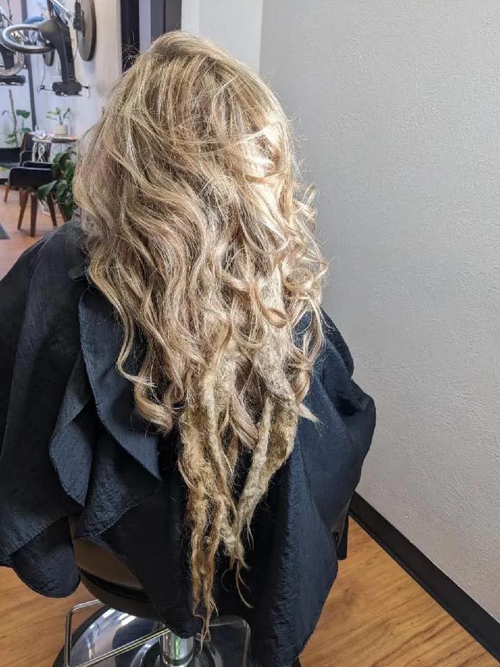 A woman with long blonde hair is sitting in a chair in a salon.