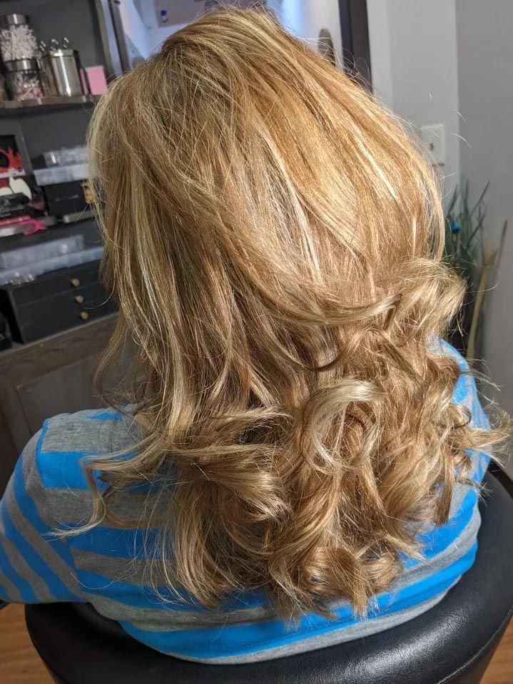 A woman is sitting in a chair with her hair in a half up half down hairstyle.