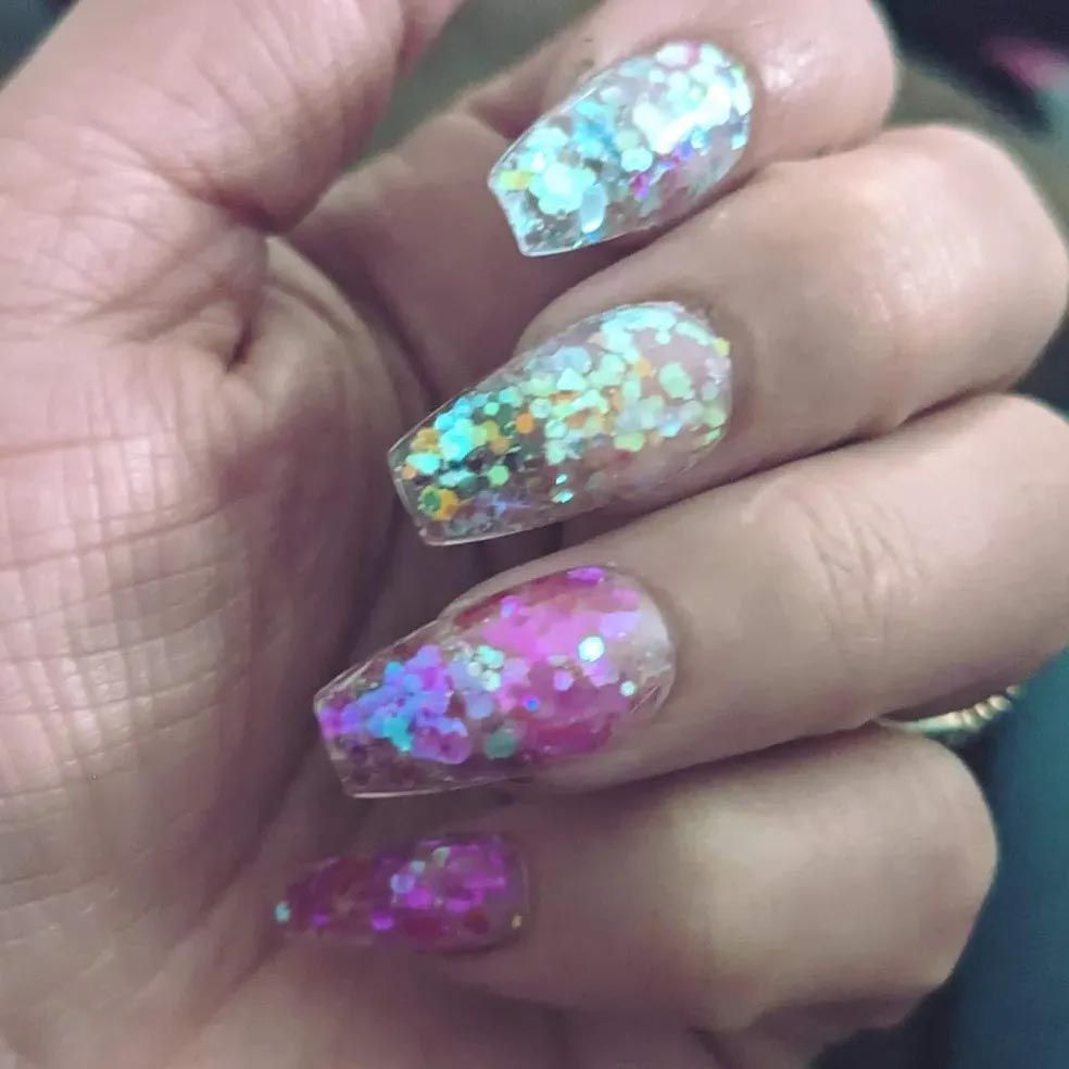A close up of a woman 's nails with glitter on them