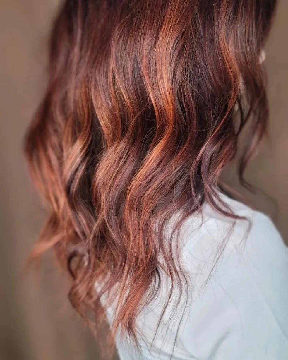 A close up of a woman 's hair with red highlights.