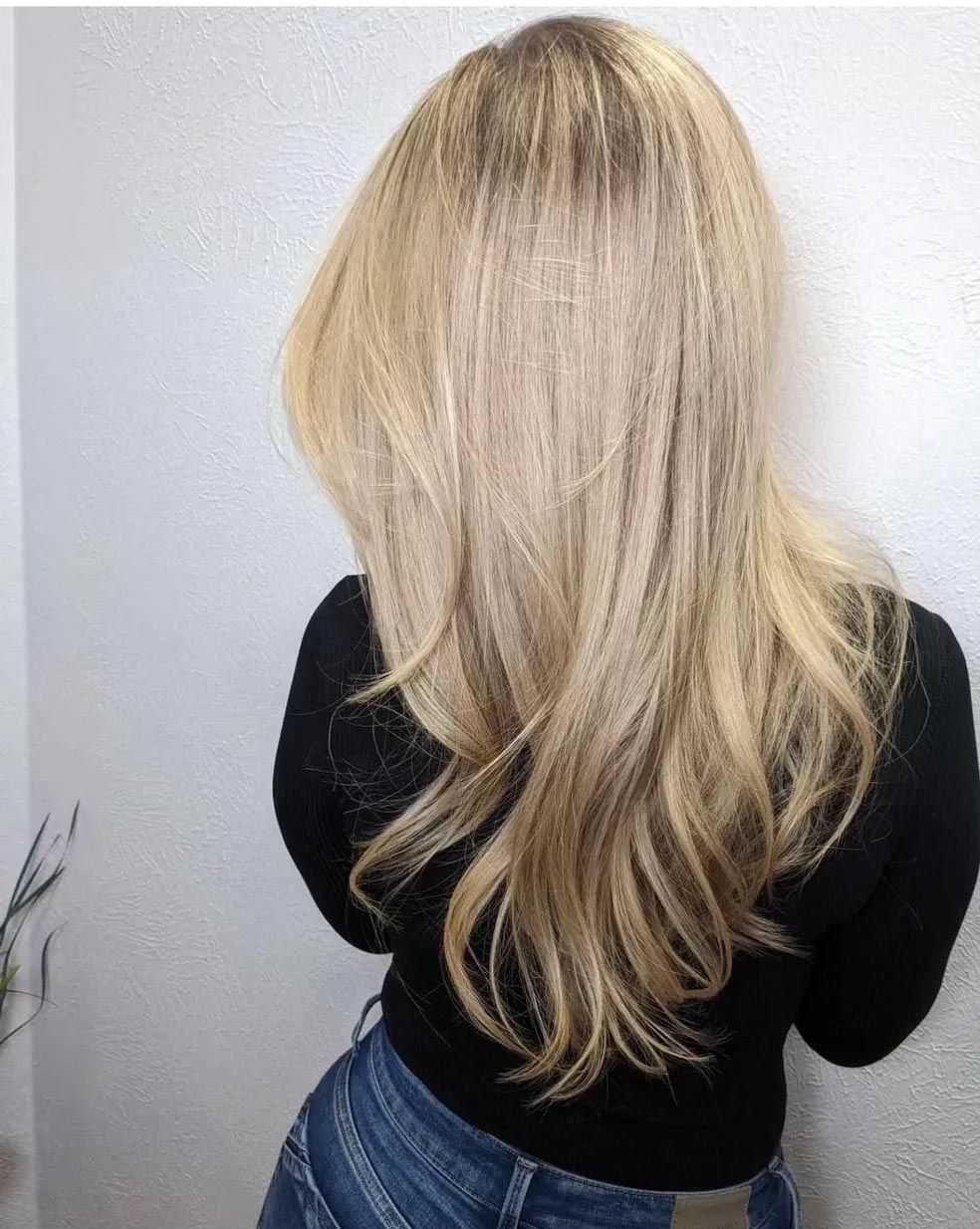 A woman with long blonde hair is wearing a black shirt and jeans.