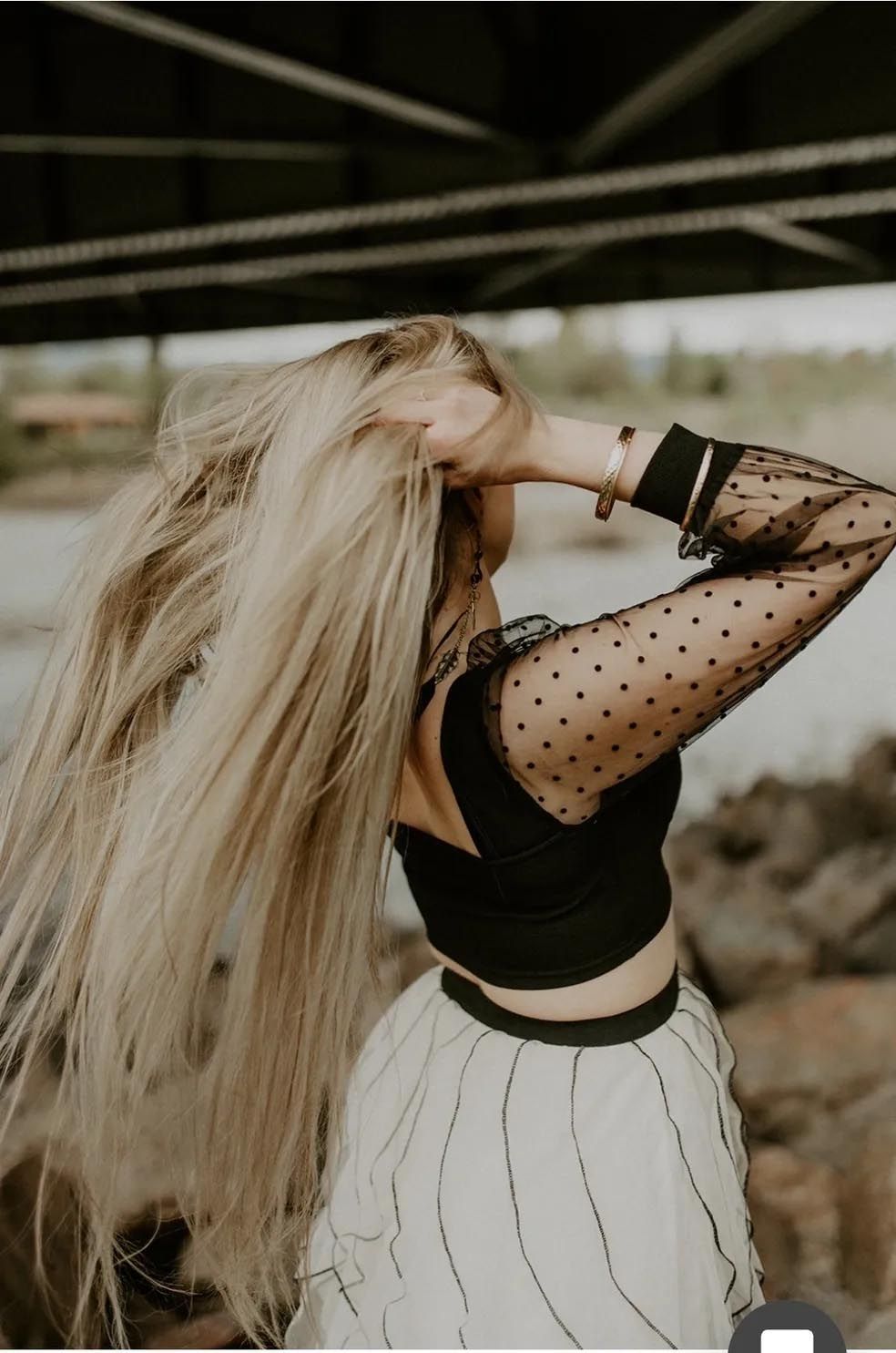 A woman with long blonde hair is standing under a bridge.