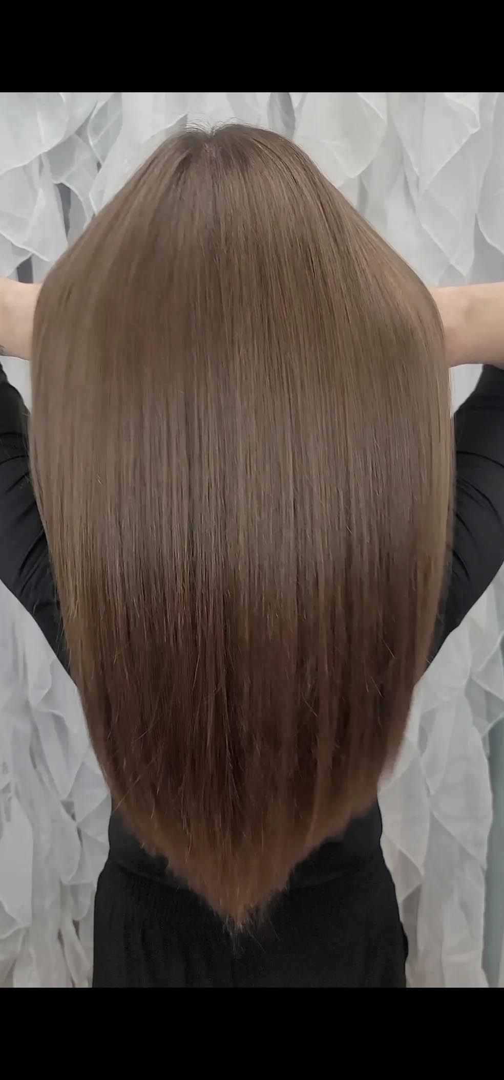 The back of a person 's head with a very long haircut.