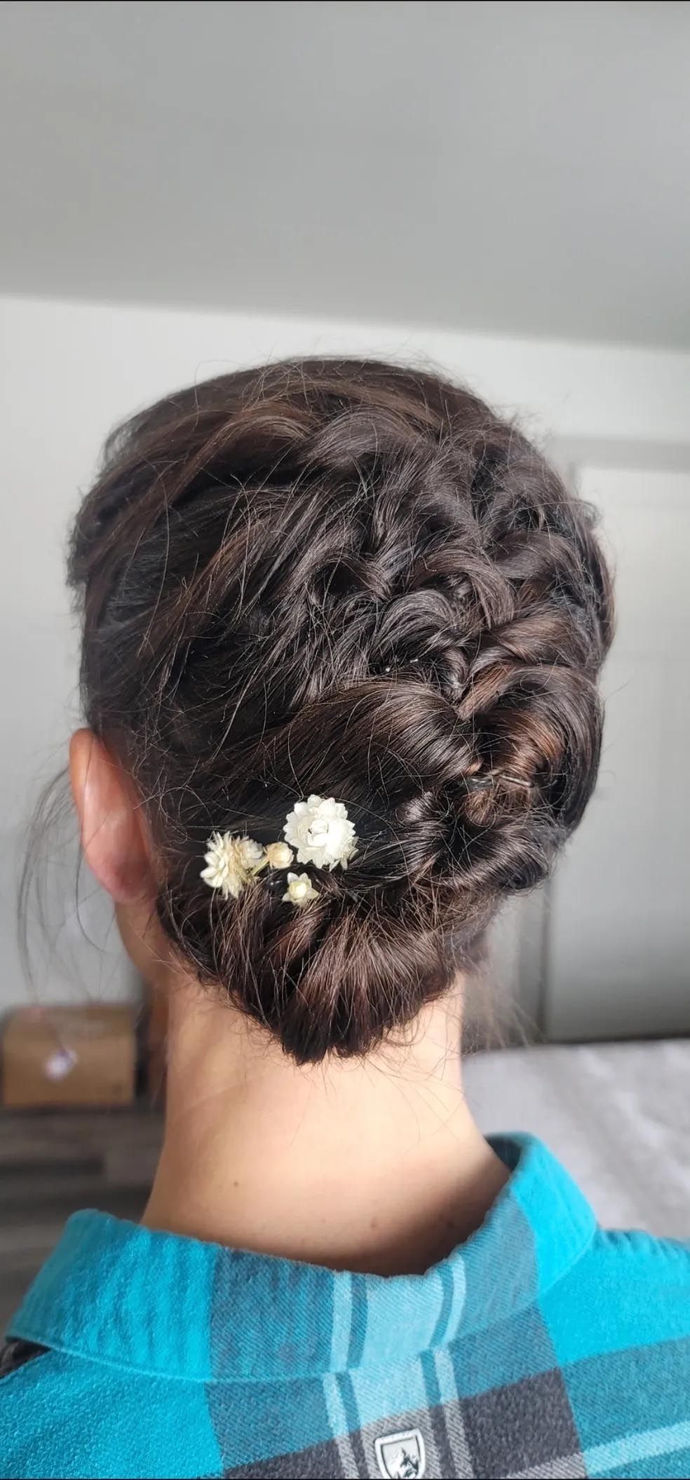 The back of a woman 's head with a bun and flowers in her hair.