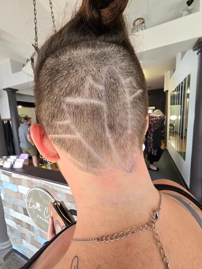 The back of a woman 's head with a shaved design on it.
