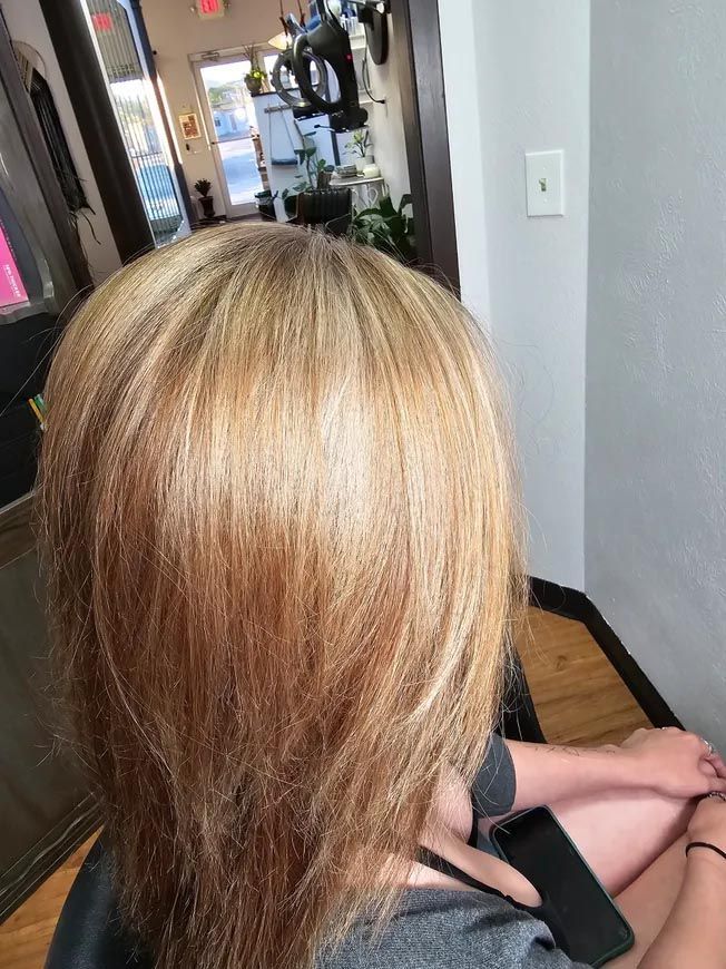 A woman with blonde hair is sitting in a chair in a salon.